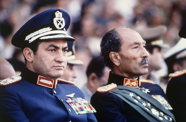 Egyptian President Anwar A-Sadat (R), and Vice President Hosni Mubarak, both dressed in military honor uniforms, attend a military parade during which the former was assassinated, Cairo, October 6, 1981.