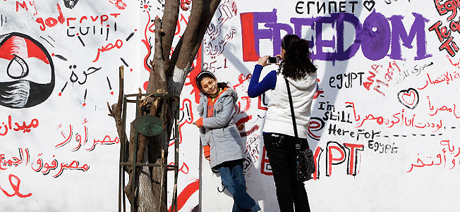 Young Egyptians take photographs of themselves standing in front of newly-painted murals on a street leading off from A-Tahrir Square, downtown Cairo, Egypt, February 13, 2011.